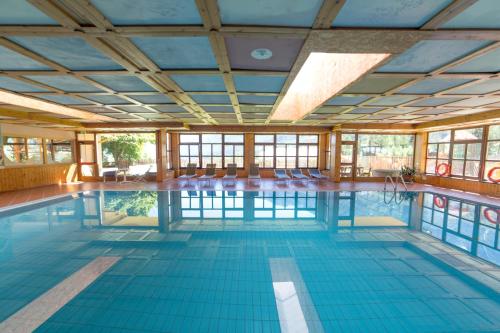 迪马罗Hotel Sancamillo的大型室内游泳池设有蓝色瓷砖地板和窗户
