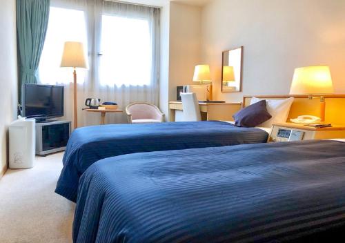 札幌HOTEL LiVEMAX Sapporo Ekimae的酒店客房设有两张床和电视。