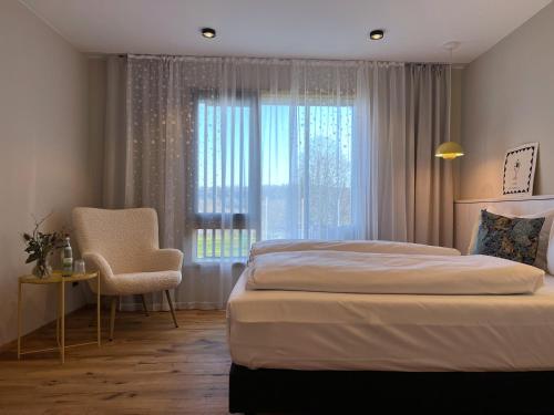 Sulzfeld am MainHotel-Weingut Bernard的卧室配有床、椅子和窗户。