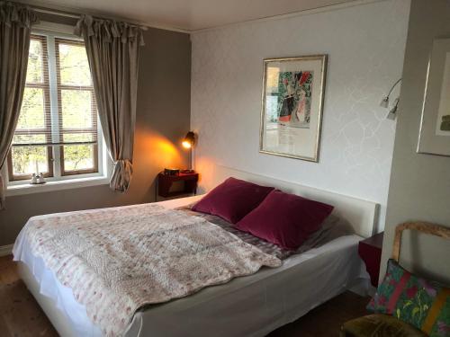 Svelvik罗尔维克别墅公寓的一间卧室配有一张带紫色枕头的大床