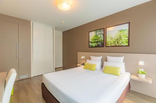 瑟松塞维涅雷恩-瑟松塞维涅城市公寓酒店的卧室配有一张带黄色枕头的大型白色床。