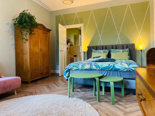 宾斯霍滕De Oude Pastorie的一间卧室配有床、两张绿桌和一张床