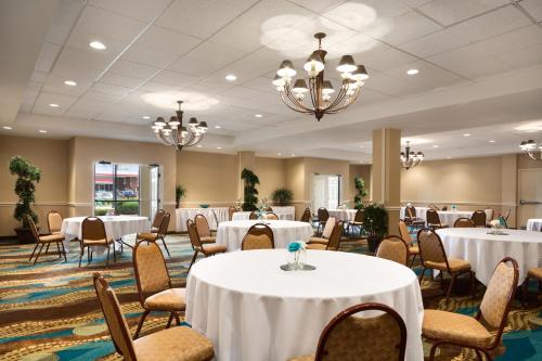 威奇托威奇托市区会展中心假日套房酒店的宴会厅配有白色的桌椅和吊灯。