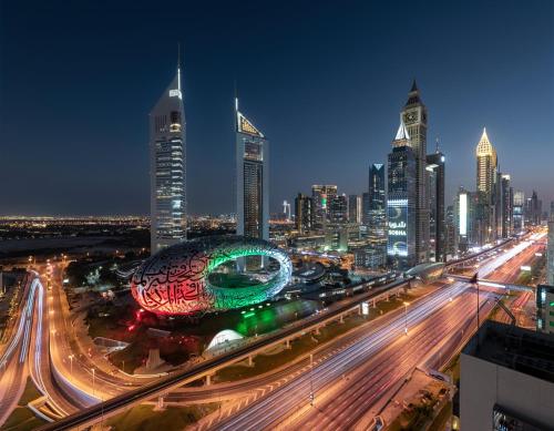 迪拜Millennium Plaza Downtown, Dubai的夜间城市天际线与高速公路上的交通