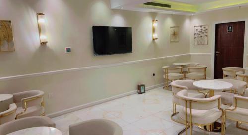 吉达Ghima Jeddah的客房设有桌椅和平面电视。