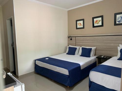 博西坎加Summit Beach Hotel Boiçucanga的酒店客房 - 带两张带蓝色枕头的床