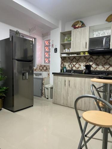 伊塔圭Lindo Apartaestudio cerca al centro的厨房配有不锈钢冰箱和桌子