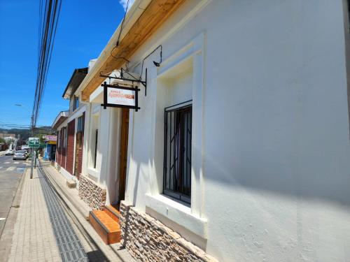 孔斯蒂图西翁Hospedaje Ahumada的街道边有标志的白色建筑