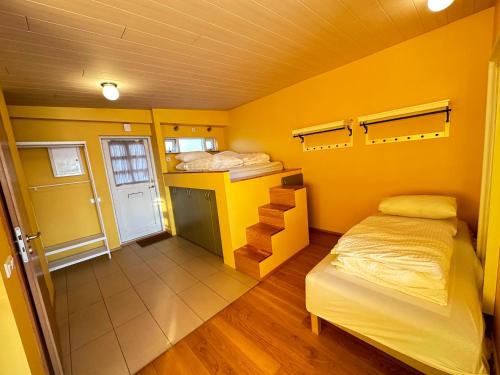 雷克雅未克An elegant studio apartment in Reykjavik - Great Location的一间卧室拥有黄色的墙壁和一张床,并拥有楼梯