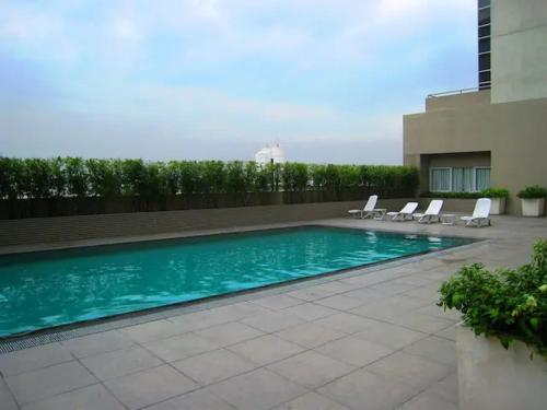 马尼拉BGC Private Apartments的一座带躺椅的游泳池位于大楼旁