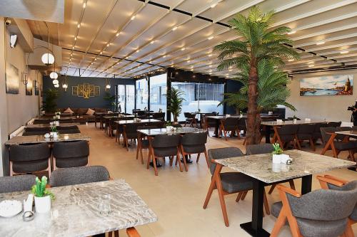 伊斯坦布尔Kerthill Hotel的一间设有桌椅的餐厅,并种植了棕榈树