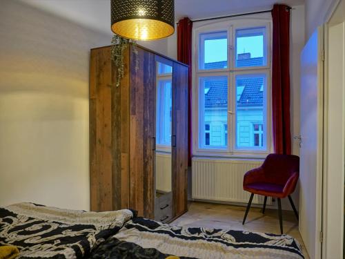 哈弗尔河畔勃兰登堡"HOGULU" Brandenurg Neustadt, Balkon, Küche, Wassernähe的一间卧室配有一张床、一张红色椅子和一个窗户