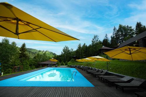 Rozhanka NizhnyayaМедовий двір的一个带黄色遮阳伞和椅子的游泳池