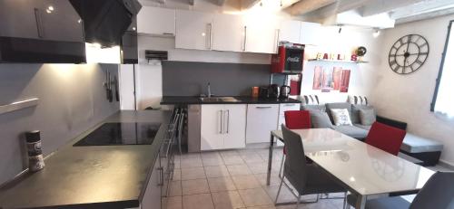 阿尔勒Maison de ville centre arles的厨房配有白色橱柜和红色椅子的桌子