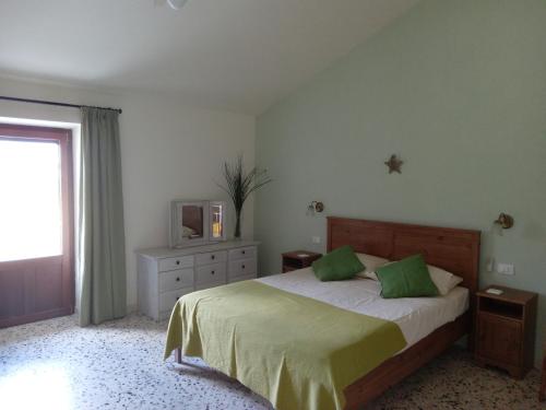 CasoliLe Farfalle Abruzzo的一间卧室配有一张带绿色枕头的床和电视。