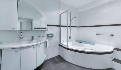 SteinenBoutique Wellnesshotel Landmann的白色的浴室设有水槽和浴缸。