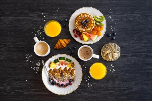 霍宁斯沃格美景旅馆的一张桌子,上面放着两盘早餐食品和饮料