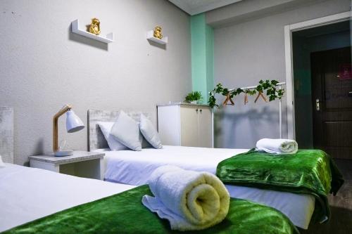 瓦伦西亚Bioparco Apartment的一间卧室配有两张带绿色床单和毛巾的床。