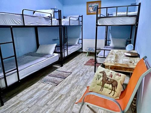 第比利斯Tbil Home Hostel的客房设有三张双层床、一张桌子和一把椅子