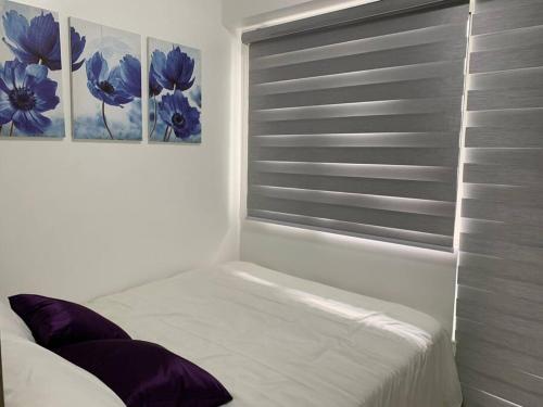 马尼拉Katei elegantly designed 1-bedroom facing amenity的卧室设有窗户,墙上挂有两幅画作