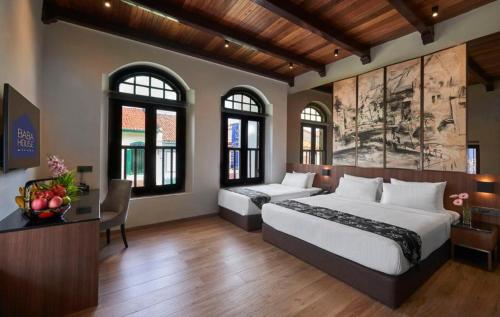 马六甲Baba House Melaka的一间卧室设有两张床、一张桌子和窗户。