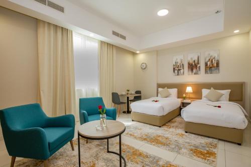 富查伊拉Platinum Coast Hotel Apartments的酒店客房带两张床和一张桌子以及椅子。