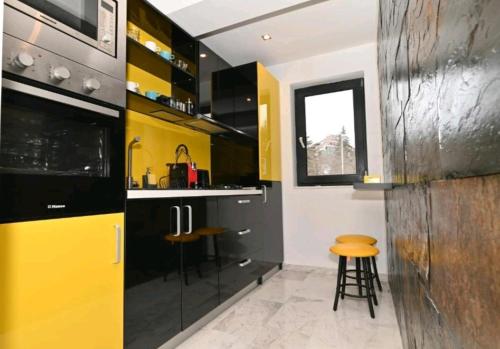 普雷代亚尔R&B Studio的厨房配有黄色和黑色橱柜和凳子