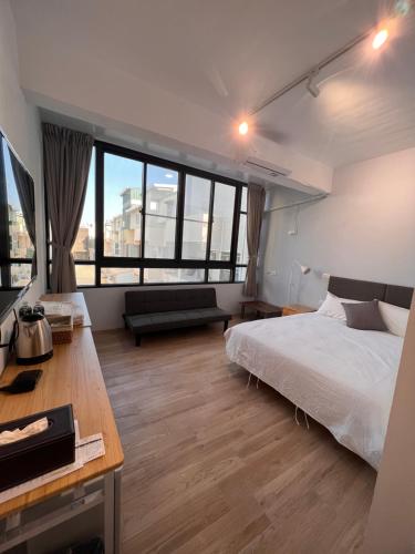 茄萣路科民宿的卧室配有一张床、一张书桌和窗户。