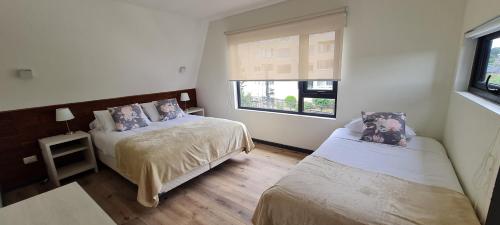 巴拉斯港Patagonia Route Apartments的一间卧室设有两张床和窗户。