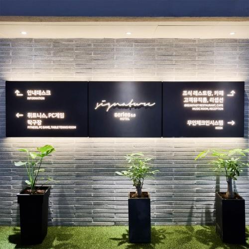 大邱Daegu Seongseo Hotel Series 5.0的墙上有标牌的两株盆栽植物