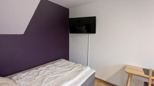 杜塞尔多夫TH Exclusive的一间卧室配有一张床和紫色的墙壁