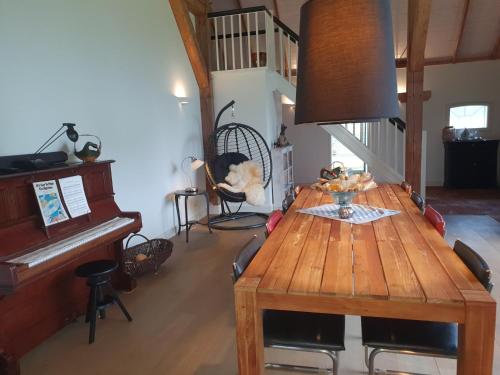 福尔登B&B Joostink in Vorden的一间带木桌和钢琴的用餐室