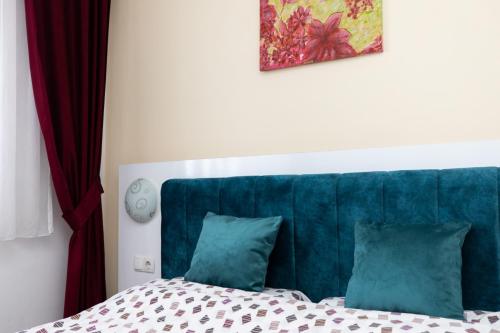 普里什蒂纳Dodona ApartHotel in Prishtina的一张带蓝色床头板的床和两个枕头