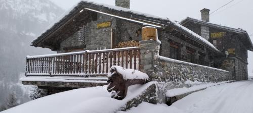 瓦尔格里森凯Hotel & Restaurant Perret - Mountain People的房子前面的雪覆盖的房子