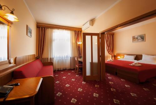 布拉格阿斯卡尼亚酒店的酒店客房配有红色的沙发和床。