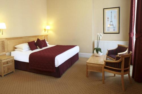 伦敦白金汉农庄酒店的酒店客房带一张大床和一把椅子