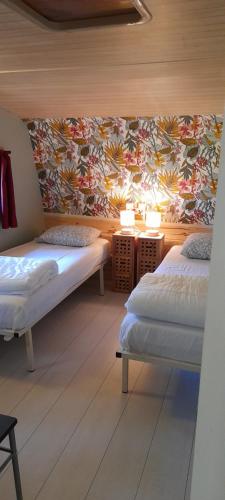 CamuracChalet et mobil homes dans la montagne au Camping les Sapins的一间卧室设有两张床,墙上贴有壁纸。