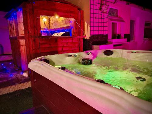 布莱克浦Captivating 4-Bed Hot Tub House in Blackpool的浴室配有带绿色和粉红色照明的浴缸。