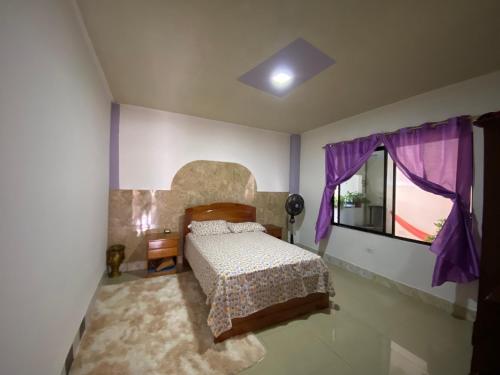 巴克里索莫雷诺港Casa en san Cristobal的一间卧室配有一张床和一个带紫色窗帘的窗户