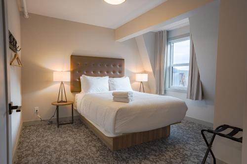 班夫Basecamp Suites Banff的一间卧室配有一张带两盏灯的床和一扇窗户。