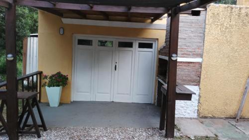 拉佩德雷拉Las Hortensias Monoambiente的一个带白色门和木制凉棚的车库
