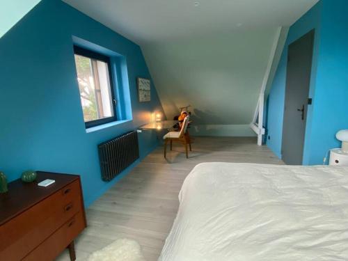 康卡勒La maison des Rimains的一间拥有蓝色墙壁的卧室、一张床和窗户