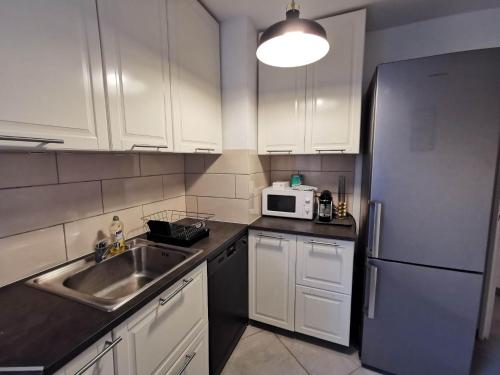 诺瑟尔Appartement Noisiel 77 (proche Disneyland & Paris)的厨房配有白色橱柜、水槽和冰箱。
