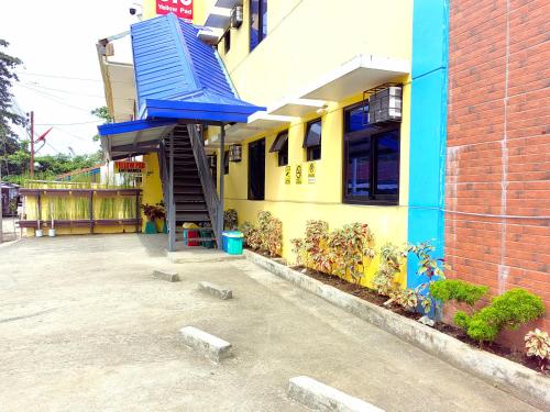 达沃市YellowPad Hotel (SM-Eco)的前面有蓝色楼梯的黄色建筑