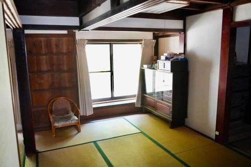 佐渡市佐渡島に残る築130年の伝統的な古民家｜東夢的客房设有椅子和大窗户。