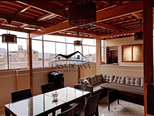 纳斯卡Hostal Casa de Ana的餐厅设有桌椅和大窗户。