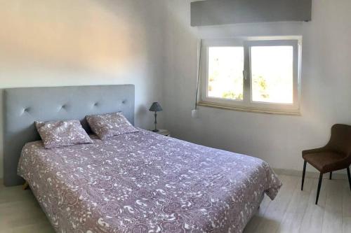 阿尔戈什Superbe villa avec piscine en algarve的一间卧室配有一张带紫色棉被的床和窗户。