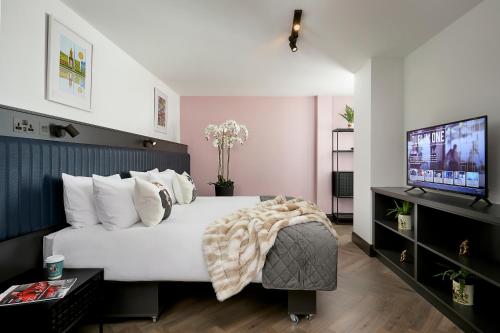 都柏林Dublin One的卧室配有白色的床和平面电视。