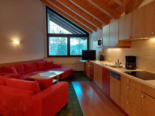 莱尔莫斯Landhaus Gerber的一间带红色沙发的客厅和一间厨房