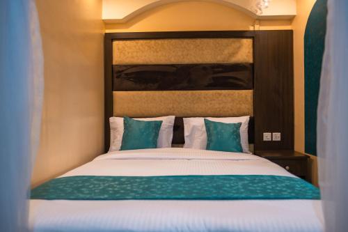 KikuyuGardens Executive Suites的一间卧室配有带绿色和白色枕头的床